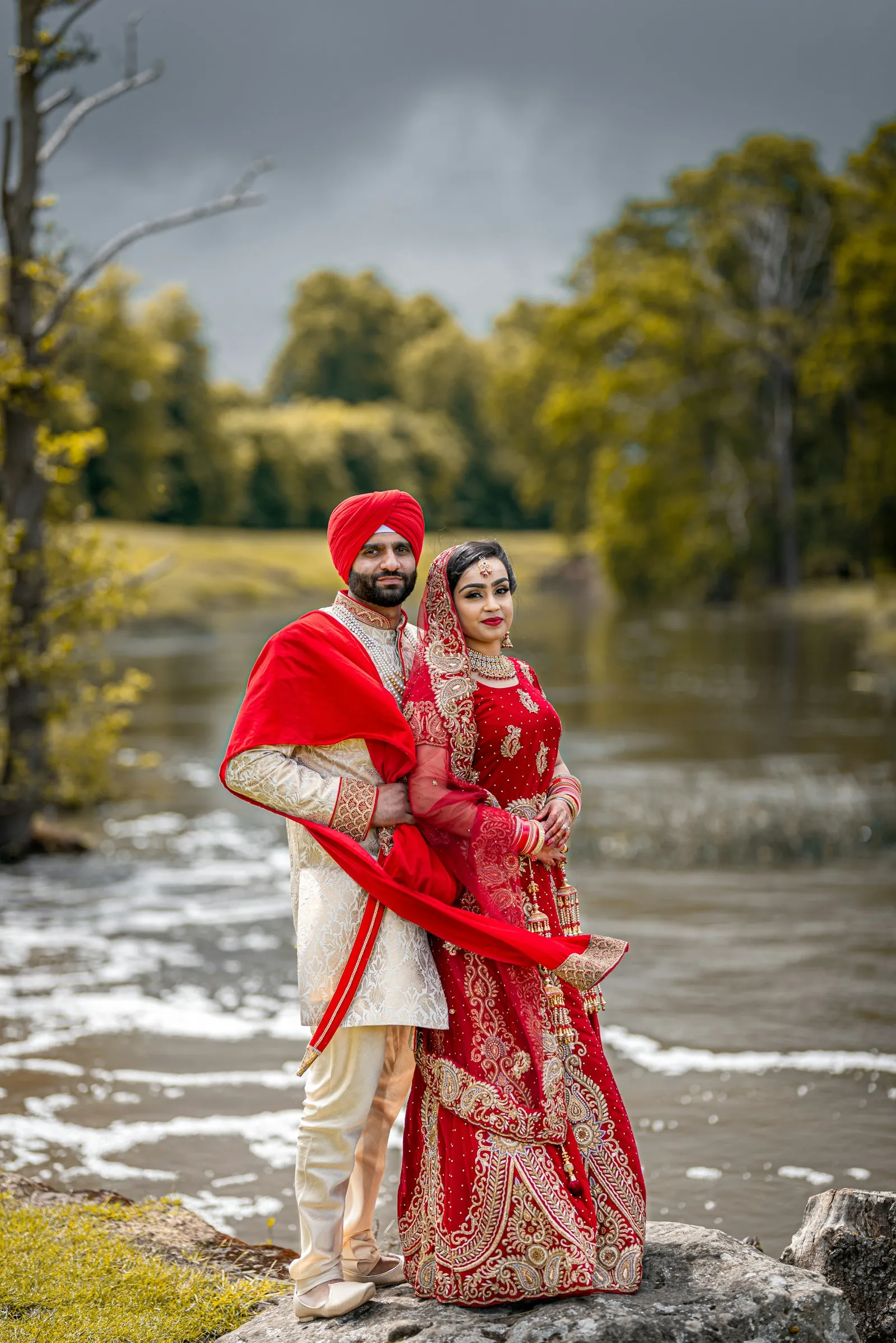 Couple in red wedding attire by a river